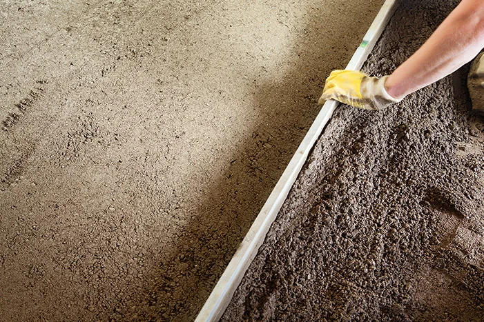 Person verteilt Schüttung mit Richtlatte